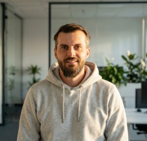Tomasz Kościański – doświadczony trener i wykładowca w Akademii Komputerowej w nowoczesnym biurze.